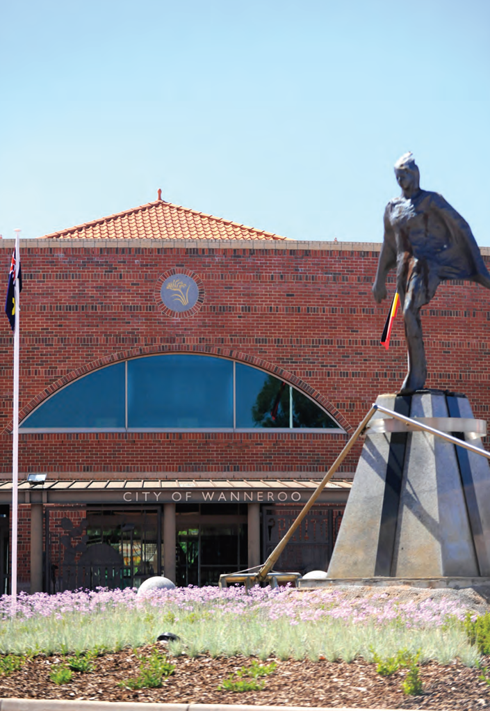 A statue of a person in front of a brick building

Description automatically generated
