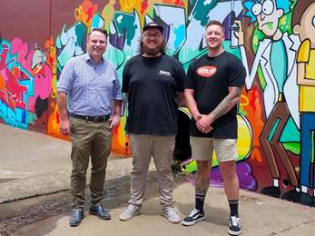 A group of men standing in front of a wall with graffiti

AI-generated content may be incorrect.