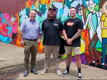 A group of men standing in front of a wall with graffiti

AI-generated content may be incorrect.